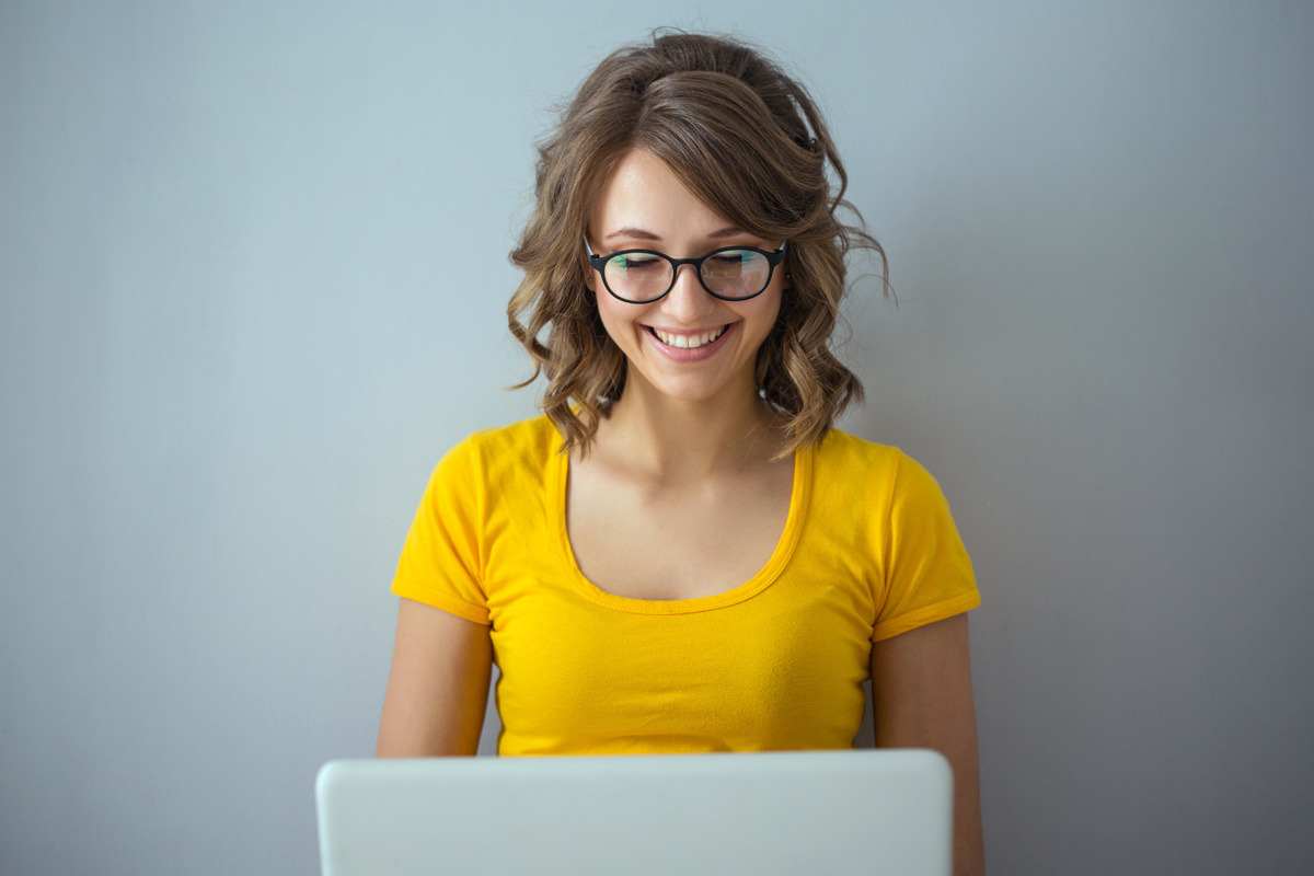 Femme avec des lunettes et tee shirt jaune actualisation pôle emploi ordinateur